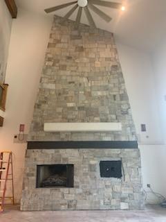Interior stone fireplace wall with a white mantel