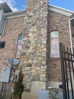 Stone-clad exterior chimney rising along a house wall